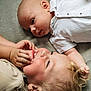 Leo is registered to the contest to win money with this photo: baby, child, infant, smiling, lying_down, white_shirt, curly_hair, blond_hair, skin, face, hand, toddler, sibling, family, candid, close_up, expression, soft_surface, indoor, cute