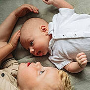 Leo joined the competition — help win amazing prizes! baby, child, siblings, infant, toddler, lying_down, blanket, white_shirt, beige_shirt, face, head, skin, cute, expression, interaction, family, indoors, soft_texture, portrait, closeup