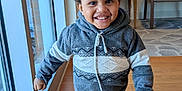Princeton is registered to the contest to win money with this photo: child, toddler, smiling, walking, hoodie, pants, sneakers, indoor, window, lamp, chair, floor, happy, person, portrait, daylight, home, furniture, carpet, artwork