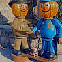 Winston joined the competition — help win amazing prizes! pumpkin, statue, dog, firefighter, police_officer, handshake, outdoor, stone_wall, sidewalk, pumpkin_head, costume, small_dog, sunlight, decorations, fall, holiday, animal, pet, friendship, festive