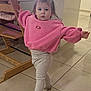 toddler, child, pink_sweatshirt, silver_shoes, standing, high_chair, wooden_furniture, tile_floor, indoor, pose, little_girl, long_sleeves, pants, hair_tied, cute, expression, person, home, floor, young_child