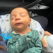 Nasser is registered to the contest to win money with this photo: newborn, baby, sleeping, onesie, pacifier, bottle, hand, car_interior, seat, blanket, infant, child, clothing, person, peaceful, resting, cute, feeding, young, transportation