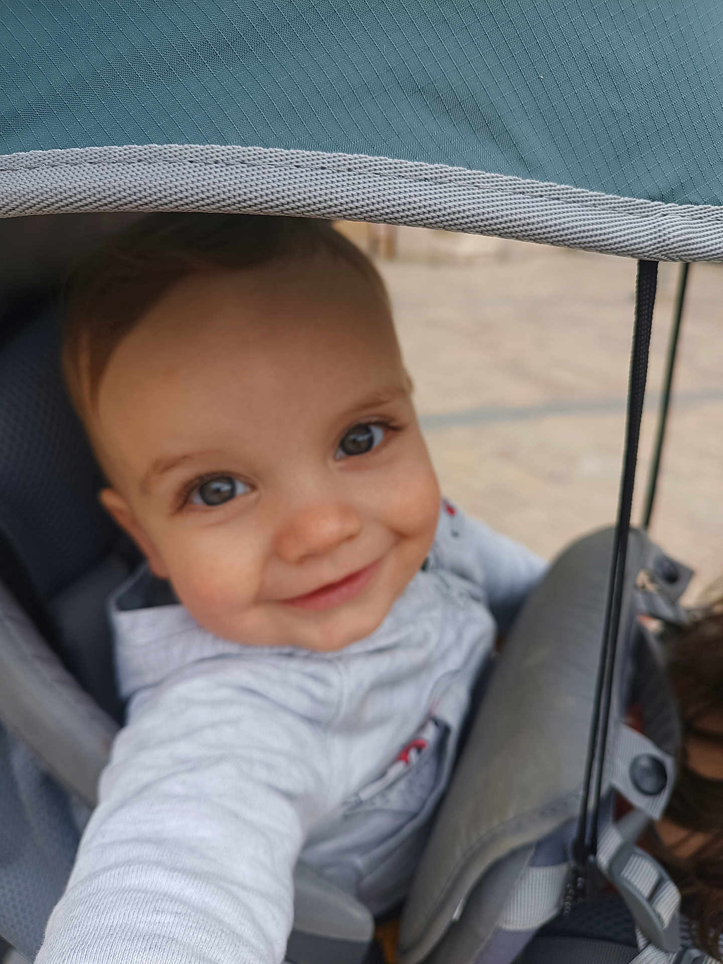 Léandre a rejoint le concours — aidez-le/la à gagner de superbes lots ! baby, infant, child, stroller, stroller_canopy, canopy, seat, harness, smile, eyes, hand, hood, jacket, portrait, happy, outdoor, pavement, playful, closeup, baby_clothing