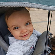 Léandre participe au concours pour gagner de l'argent avec cette photo : baby, infant, child, stroller, stroller_canopy, canopy, seat, harness, smile, eyes, hand, hood, jacket, portrait, happy, outdoor, pavement, playful, closeup, baby_clothing