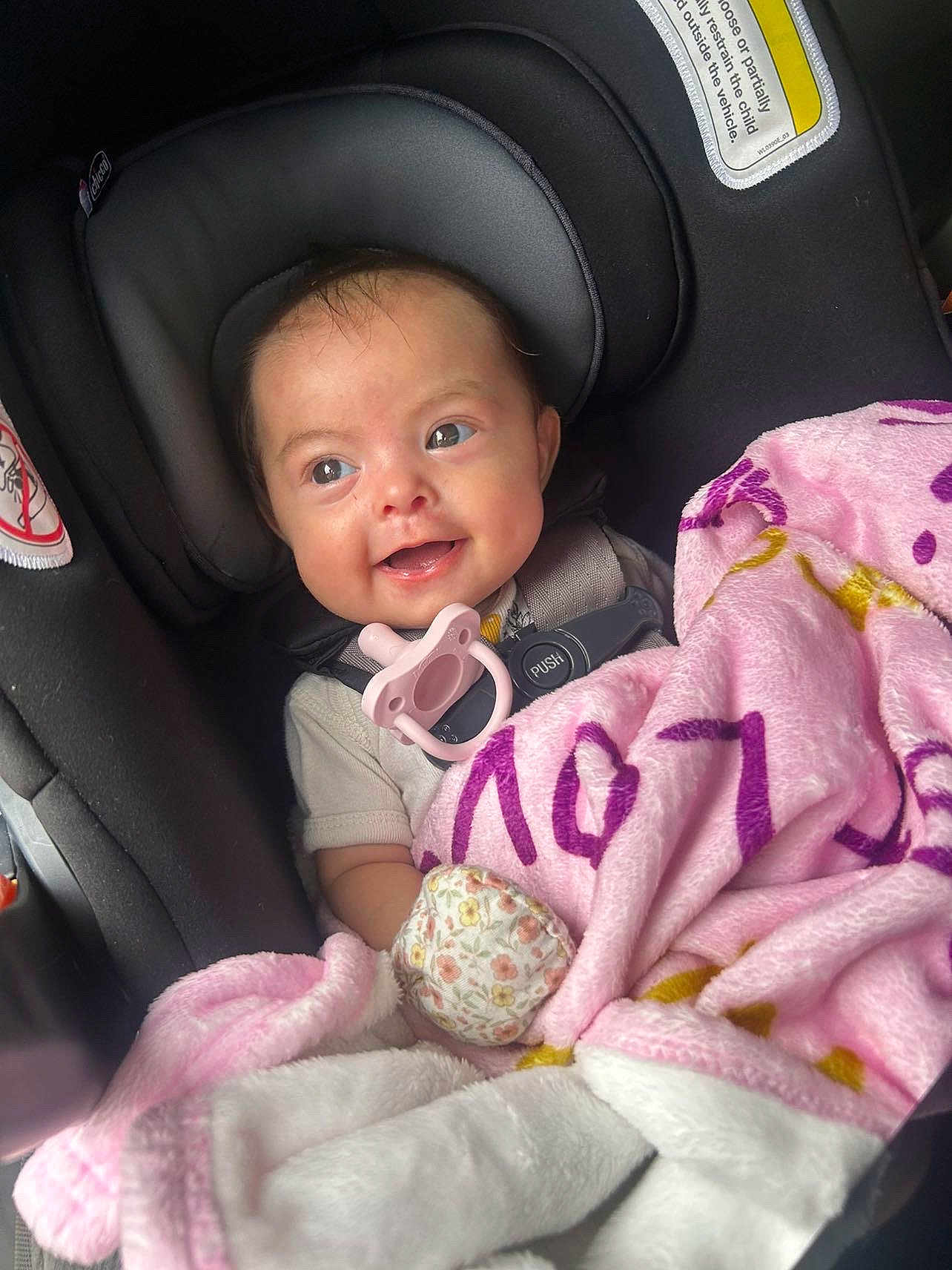 Karmyn is registered to the contest to win money with this photo: baby, car_seat, blanket, pacifier, smile, infant, child, seatbelt, clothing, pink, cute, happy, indoors, face, person, young_child, safety, head_support, soft_texture, comfort