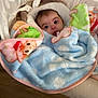 baby, blanket, child, colorful, cute, face, furniture, indoor, infant, lacy, looking, patterned, person, plush, sitting, soft, surprised, toddler, wood_floor, wrapped