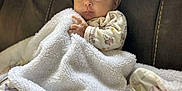 Karmyn is registered to the contest to win money with this photo: baby, blanket, couch, pacifier, infant, face, hand, clothing, fabric, soft, comfort, seated, indoors, cute, child, person, portrait, rest, warm, expression
