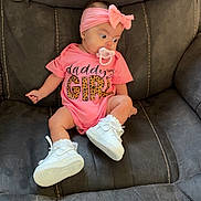Karmyn is registered to the contest to win money with this photo: baby, infant, girl, pink_headband, bow, pacifier, pink_onesie, white_sneakers, couch, gray_couch, seated, child, clothing, footwear, indoor, cute, young_child, portrait, baby_fashion, headwear