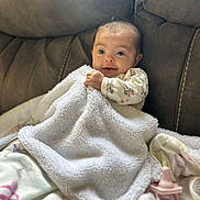 Karmyn is registered to the contest to win money with this photo: baby, blanket, couch, pacifier, infant, soft, cozy, child, face, smile, clothing, furniture, indoor, portrait, sitting, cute, young, comfort, relax, home
