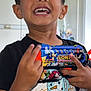 child, boy, smiling, toy_gun, sonic_the_hedgehog, indoor, black_tshirt, snowman_graphic, happy, portrait, person, short_hair, playful, hand, fingers, teeth, face, casual_clothing, background, home