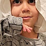 child, face, eyes, hood, cloth, grey_shirt, patterned_shirt, hand, curious, portrait, indoors, young, childhood, expression, casual_clothing, closeup, person, cute, thinking, light_background