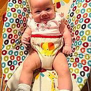 Stella joined the competition — help win amazing prizes! baby, infant, smiling, baby_seat, colorful, patterned, animal_print, giraffe, elephant, socks, cute, child, happy, indoors, wood_floor, clothing, portrait, playful, baby_girl, seat