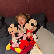 Mia a rejoint le concours — aidez-le/la à gagner de superbes lots ! blanket, child, comfort, couch, cushion, cute, girl, home, indoor, mickey_mouse, minnie_mouse, person, pigtails, plush_toys, red_clothing, seated, smiling, soft_toys, tights, toy