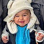 baby, child, smile, blue_bib, fluffy_hat, bear_ears, stroller, bundle, happy, cute, infant, clothing, warm, hand, face, baby_accessory, blanket, safety_strap, portrait, outdoor