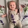 Livio participe au concours pour gagner de l'argent avec cette photo : baby, infant, smiling, romper, flowers, purple_flowers, red_flowers, fabric, rope, soft_surface, cute, child, portrait, happy, skin, hands, feet, laying, indoors, natural_light