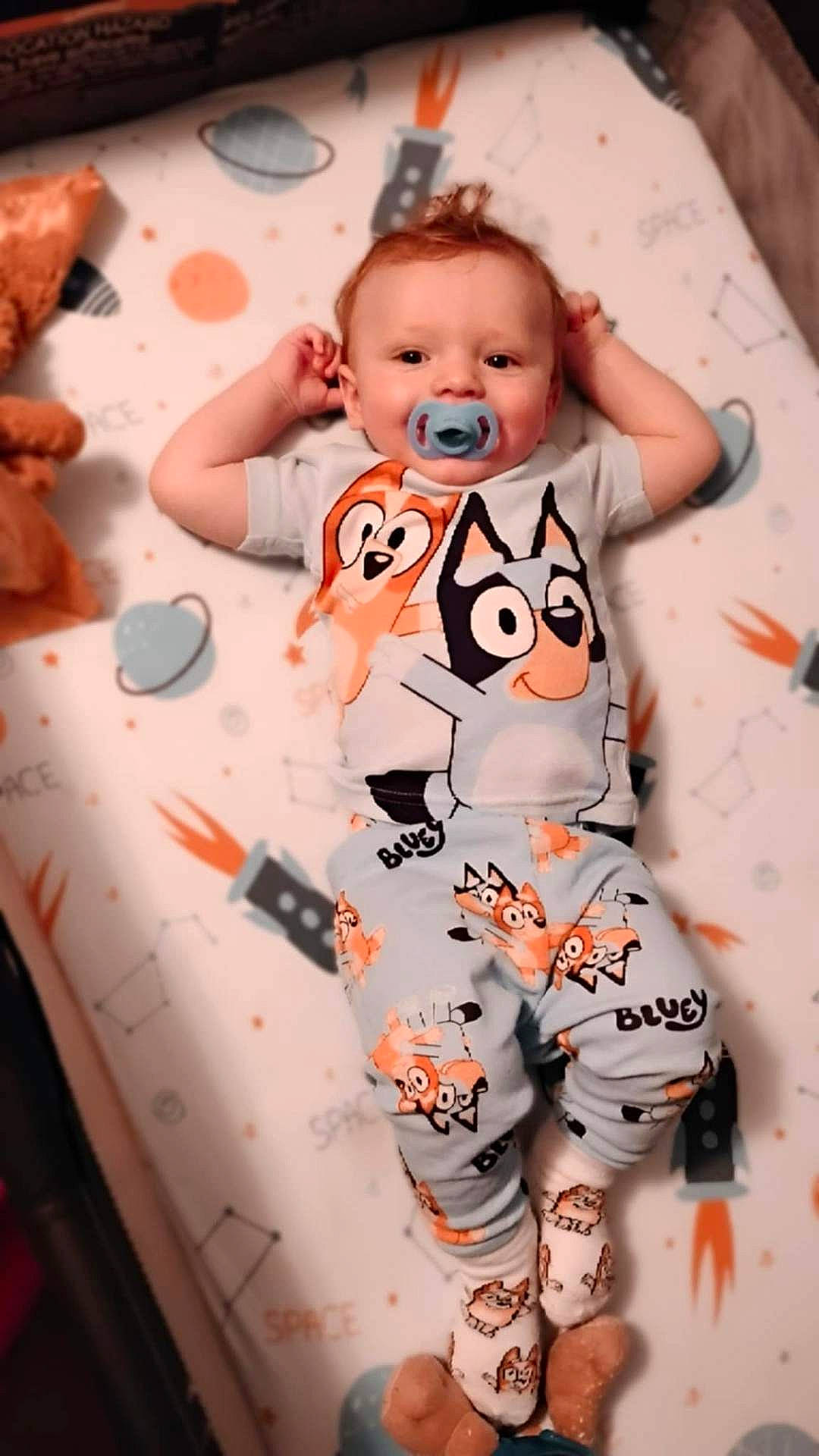 Elijah joined the competition — help win amazing prizes! baby, cartoon, child, colorful, cozy, cute, dog, indoors, infant, lying_down, mattress, pacifier, pajamas, planet, rocket, sleepwear, smiling, soft_toy, space_theme, toy