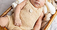 Ezekiel joined the competition — help win amazing prizes! baby, infant, child, portrait, face, wide_eyed, sitting, bassinet, wicker, knitwear, hat, romper, blanket, cozy, indoors, nursery, soft_lighting, brown, beige, photography