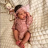 baby, bed, blanket, bow, child, face, feet, headband, indoors, infant, lace, lying_down, newborn, photography, pink_outfit, plush_toy, portrait, quilt, sleeping_area, stuffed_animal