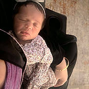 Sienna is registered to the contest to win money with this photo: baby, black_clothing, bow, bracelet, child, closeup, cute, face, floral_onesie, hand, headband, indoor, infant, newborn, peaceful, person, portrait, resting, sleeping, soft_light