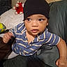Grayson joined the competition — help win amazing prizes! baby, beanie, casual_clothing, child, couch, curious, cushions, eyes, face, furniture, home, indoors, looking_away, photography, plush_toy, portrait, red_toy, sitting, striped_shirt, toddler