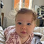 baby, infant, face, blue_eyes, hair, curly_hair, bed, blanket, clothing, pink_flower_pattern, person, indoor, portrait, child, cute, expression, skin, head, young, toddler
