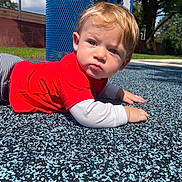 Timothy joined the competition — help win amazing prizes! toddler, child, playground, outdoor, red_shirt, striped_pants, blue_trash_can, rubber_surface, sunny, grass, trees, face, hand, crawling, young_child, casual_clothing, daylight, expression, person, park