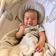 Orion joined the competition — help win amazing prizes! baby, baby_carrier, blanket, clothing, comfort, cushion, cute, dinosaur_print, face, hand, happy, head, indoors, infant, person, portrait, relaxation, smile, soft_texture, young_child