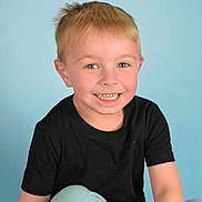 Carter is registered to the contest to win money with this photo: child, boy, smiling, portrait, blond_hair, blue_eyes, black_tshirt, light_blue_pants, casual_clothing, studio_background, happy, cute, young, human, face, sitting, indoor, childhood, youth, photography