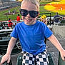 Carter joined the competition — help win amazing prizes! child, boy, sunglasses, blue_shirt, checkered_shorts, stadium, baseball_field, sports, smiling, kneeling, outdoor, daylight, crowd, yellow_bow, girl, spectators, seating, recreation, fun, happy