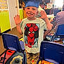 Carter is registered to the contest to win money with this photo: child, boy, graduation_cap, spiderman, tshirt, smiling, classroom, carpet, chairs, people, indoor, celebration, happy, learning, education, colorful, toys, furniture, person, casual_clothing