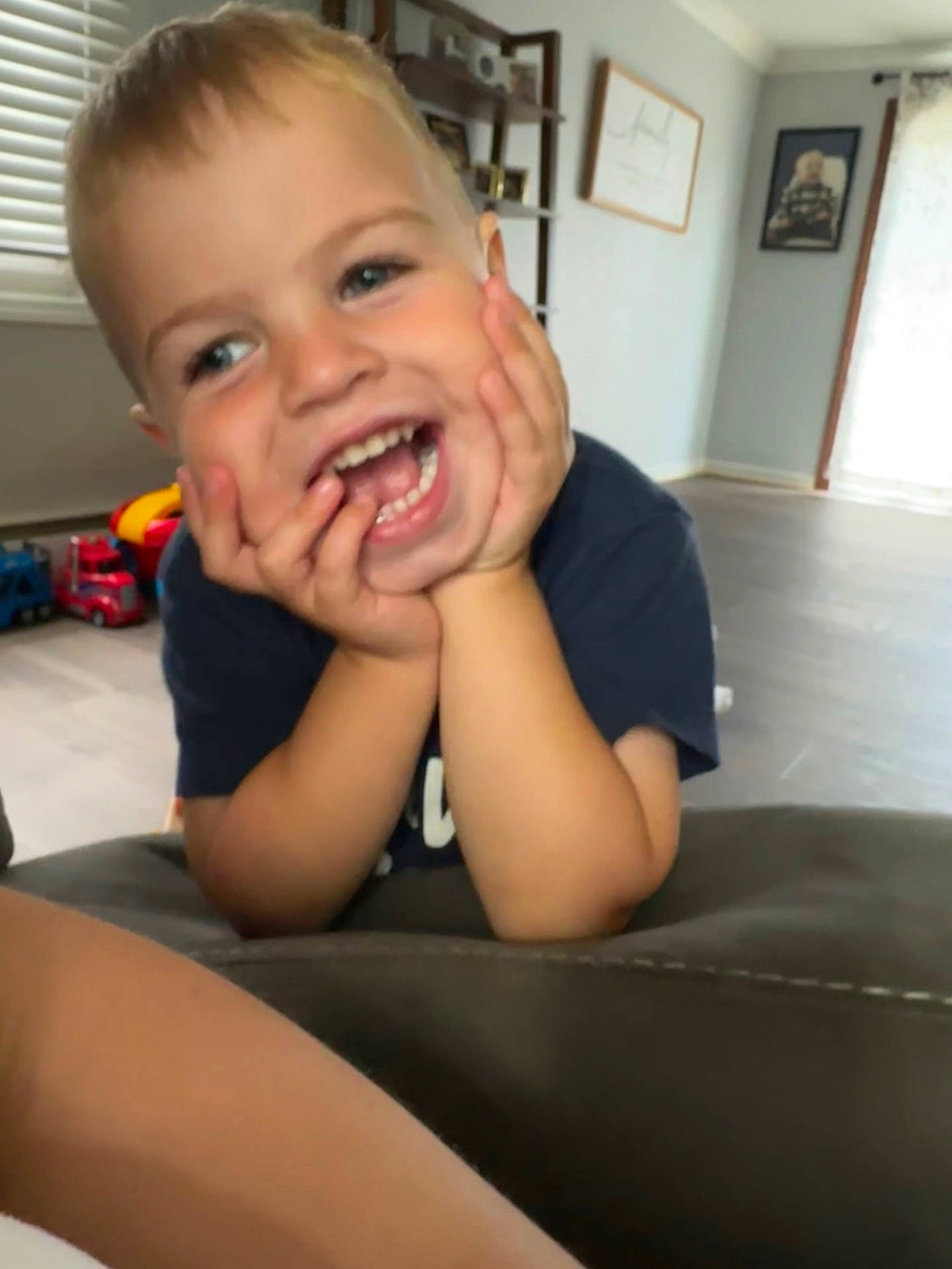 Wyatt is registered to the contest to win money with this photo: blonde_hair, boy, casual_clothing, child, curtains, cute, face, furniture, hands_on_face, happy, home, indoor, laughing, living_room, person, photography, portrait, smiling, toys, window