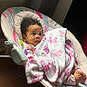 baby, blanket, baby_rocker, curly_hair, indoor, infant, patterned_blanket, pink, white, foot, child, soft_light, wood_floor, face, clothing, resting, cute, person, infant_toy, home