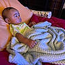 baby, infant, child, portrait, lying_down, bed, blanket, pink_bedding, pillow, clothing, striped_shirt, hand, face, eyes, indoor, bedroom, furniture, cozy, resting, photograph