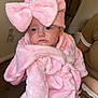Isabelle joined the competition — help win amazing prizes! baby, pink_bow, pink_robe, infant, child, person, indoor, soft_fabric, cute, sleepy, face, headwear, clothing, hand, sitting, human, skin, expression, adult_hand, background