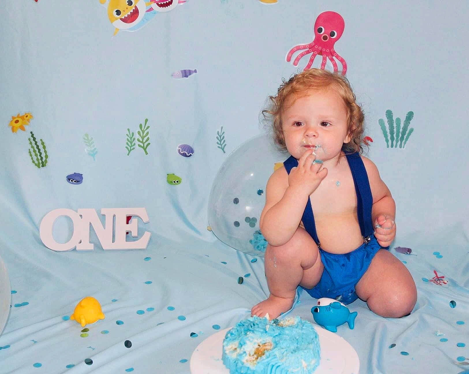 Devin Jr is registered to the contest to win money with this photo: aqua, baby, baby_products, baby_toddler_clothing, cake_decorating_supply, child, event, fun, happy, human_leg, party_supply, pattern, person, play, room, sitting, sugar_cake, thigh, toddler
