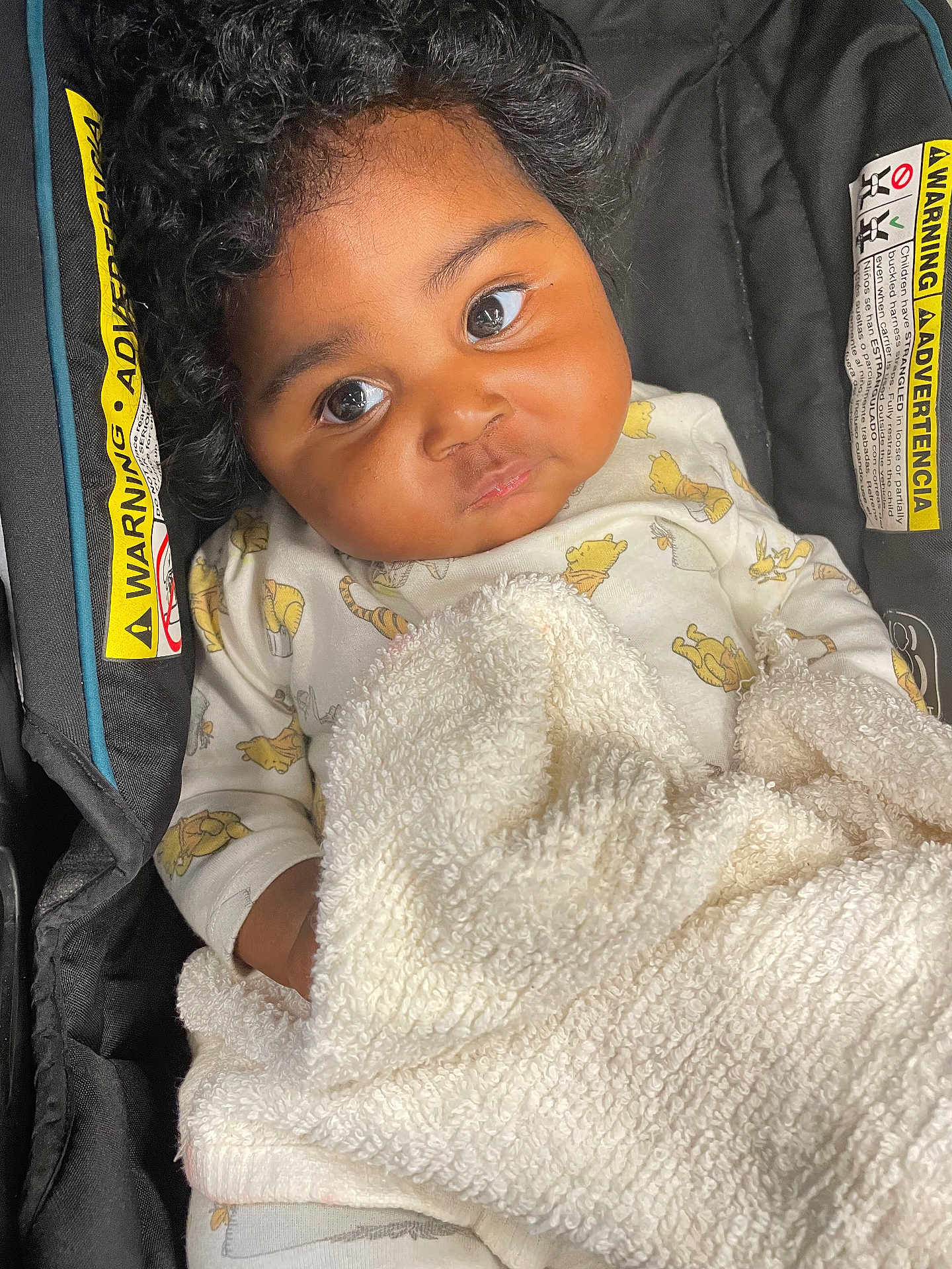 Journey is registered to the contest to win money with this photo: baby, child, curly_hair, blanket, car_seat, warning_label, clothing, cute, infant, portrait, indoors, young_child, cozy, expression, looking_up, seat, soft_texture, toddler, person, close_up