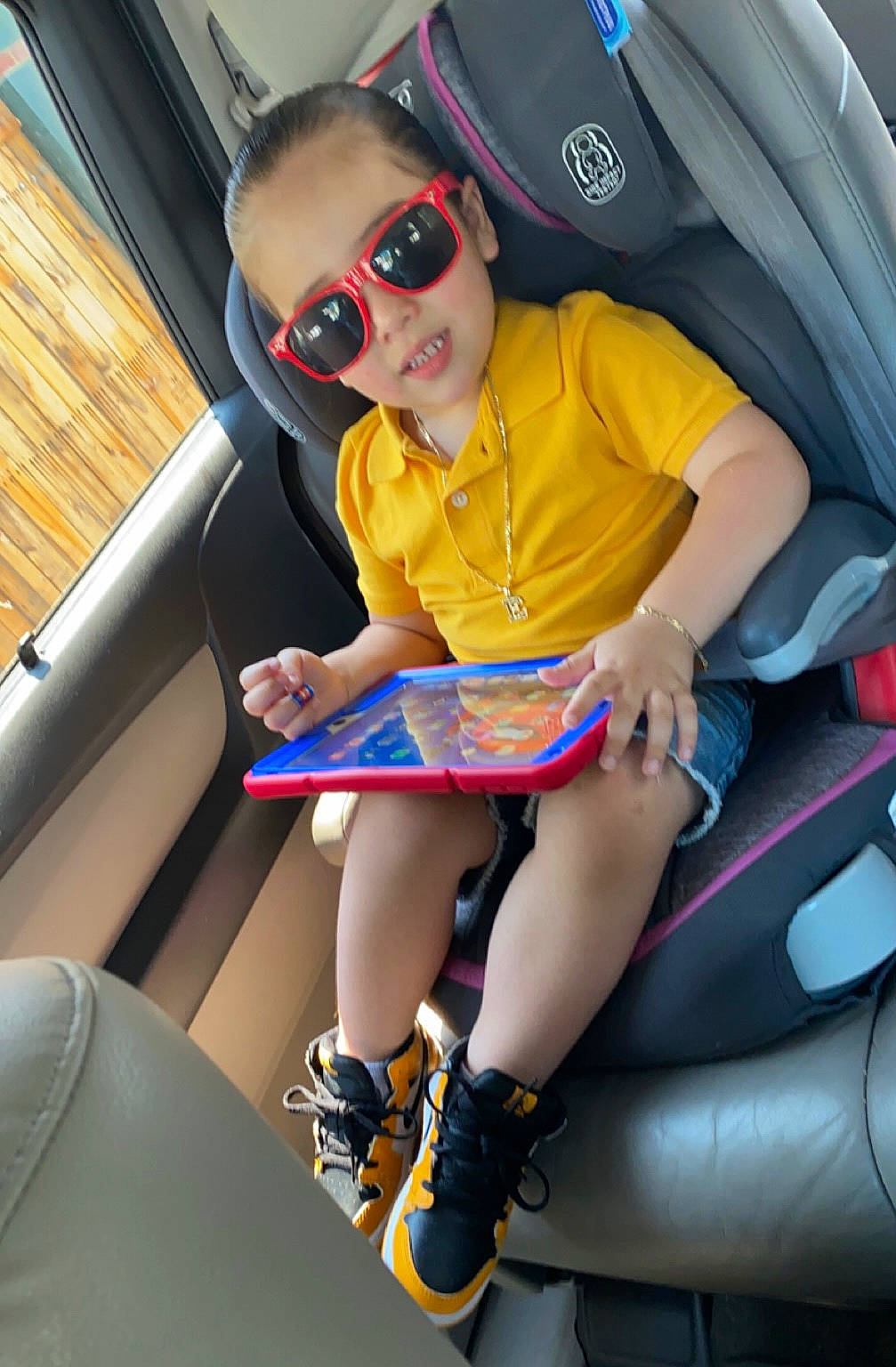 Elvin is registered to the contest to win money with this photo: auto_part, automotive_design, baby, baby_toddler_clothing, car_seat, comfort, cool, eyewear, fun, goggles, knee, lap, person, shorts, sneakers, sunglasses, thigh, toddler, vehicle_door, vision_care