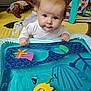 baby, blue_eyes, water_mat, toy, indoor, play_area, colorful, infant, curious, soft_lighting, carpet, plush_toy, hand, face, clothing, floor, child, early_childhood, playtime, crawling