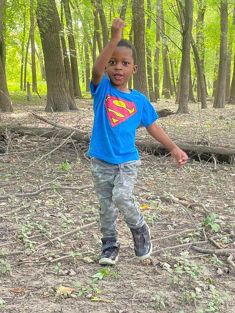 Kevin is registered to the contest to win money with this photo: child, electric_blue, forest, fun, grass, jungle, natural_landscape, people_in_nature, person, plant, recreation, soil, t_shirt, terrestrial_plant, toddler, trail, tree, trunk, walking, wood