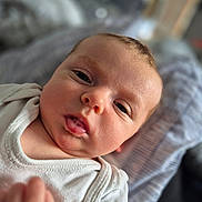 Charlotte is registered to the contest to win money with this photo: baby, infant, face, skin, eyes, mouth, drool, clothing, onesie, blanket, soft, young, child, portrait, indoor, closeup, expression, person, head, cute