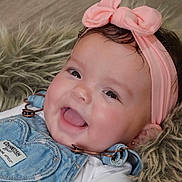 Alaya is registered to the contest to win money with this photo: adorable, apparel, baby, candid, child, close_up, cute, denim_overalls, face, fur_blanket, happy, headband, indoors, infant, person, pink_bow, portrait, smiling, soft_texture, young_child