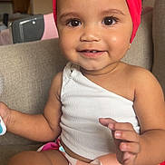 Zilyncia is registered to the contest to win money with this photo: baby, bright, casual_clothing, child, colorful_skirt, couch, curly_hair, cute, face, hands, happy, indoor, playful, portrait, red_headband, sitting, skin, smiling, toddler, white_top