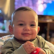Hayden is registered to the contest to win money with this photo: baby, smile, face, hand, toy, indoor, child, clothing, cute, portrait, happy, infant, young, sitting, holding, polka_dot, warm_light, background_blur, person, cozy