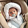 baby, car_seat, pacifier, white_jacket, hood, teddy_bear, child, infant, seatbelt, fur, cute, portrait, indoor, warm_clothing, expression, closeup, comfort, soft_toy, young_child, safety