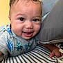Isaiah joined the competition — help win amazing prizes! baby, child, curly_hair, dinosaur_onesie, striped_sheet, pillow, smiling, closeup, face, cute, happy, person, infant, indoors, bed, hand, clothing, young_child, portrait, playful
