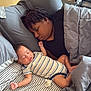 Isaiah joined the competition — help win amazing prizes! baby, adult, sleeping, bed, bedding, blanket, pillow, striped_onesie, resting, cozy, indoor, person, child, nap, pacifier, gray, comfort, peaceful, family, together
