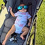 baby, stroller, sunglasses, onesie, keys, grass, outdoor, infant, child, cute, casual, reflective_sunglasses, animal_print, relaxing, sunny, footwear, baby_toddler, leisure, summer, portrait