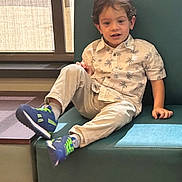 Matthew joined the competition — help win amazing prizes! child, boy, indoor, bench, window, curtains, casual_clothing, palm_tree_pattern, sneakers, blue_shoes, beige_pants, teal_cushion, wood_floor, light, smiling, hair, face, relaxed, seated, daylight