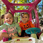 Camari Jo joined the competition — help win amazing prizes! child, toddler, toy_car, outdoor, play, cute, smile, happy, autumn, pumpkin, costume, hair_bow, greenery, sunlight, nature, playtime, pink, clothing, portrait, friends