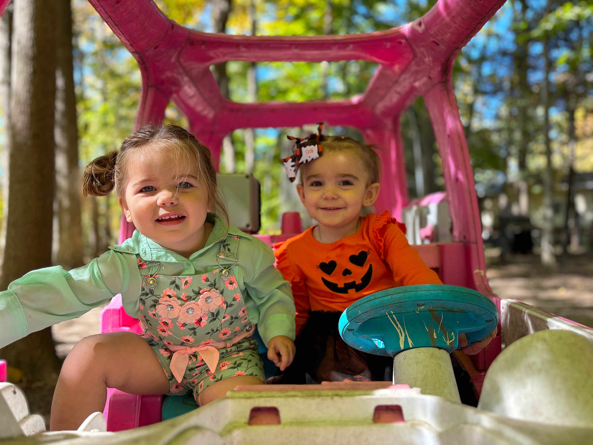 Camari Jo joined the competition — help win amazing prizes! child, toddler, toy_car, outdoor, play, cute, smile, happy, autumn, pumpkin, costume, hair_bow, greenery, sunlight, nature, playtime, pink, clothing, portrait, friends